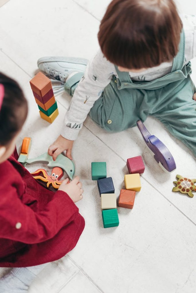 two-children-playing-with-lego-blocks-and-other-toys-3661450 Two young children playing with colorful wooden blocks indoors, fostering creativity and fun.
